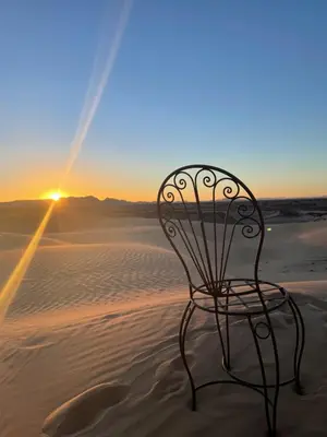 a chair sitting in the sand in the desert at Dunes Clave in Hassilabied