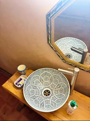 a bathroom sink and a mirror on a wooden table at Riad Ayoub Fes in Fès