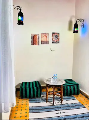 a room with a table and two ottomans at Riad Ayoub Fes in Fès
