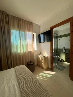 a bedroom with a bed and a bathroom with a shower at Cabo vip in Oulad Akkou