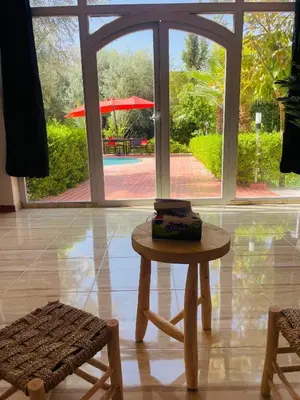 a table and a chair in a room with a window at Villa MSHolidays 3 palmiers avec piscine marrakech in Marrakech