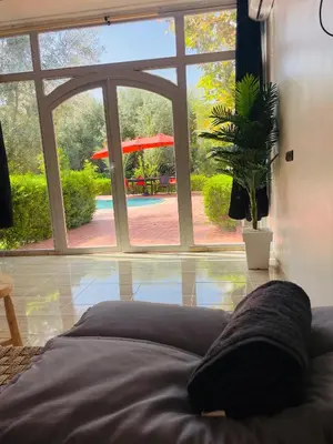 a bedroom with a large window and a potted plant at Villa MSHolidays 3 palmiers avec piscine marrakech in Marrakech