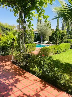 a red brick walkway leading to a yard with a pool at Villa MSHolidays 3 palmiers avec piscine marrakech in Marrakech