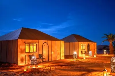 a couple of buildings in the desert at night at Merzouga Luxurious Stay in Merzouga