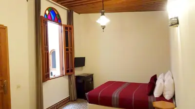 a bedroom with a bed and a stained glass window at Riad Sabah in Fès