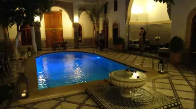 a swimming pool with a fountain in a building at Riad Sabah in Fès