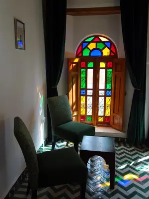 a room with chairs and a stained glass window at Riad Sabah in Fès