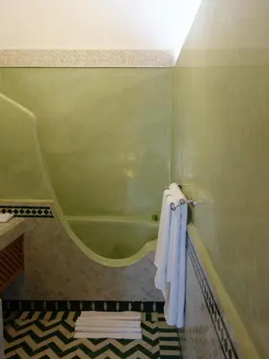 a bathroom with a tub and towels hanging on a wall at Riad Sabah in Fès