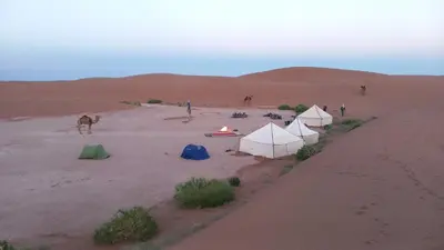 a group of tents in the desert with a fire at Camp sahara in Oulad Akkou