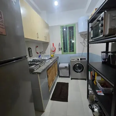 a small kitchen with a stove and a washing machine at Appartement Confortable à Chouiter in Chouiter
