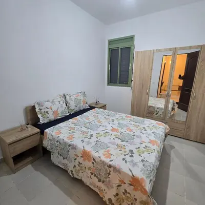 a bedroom with a bed with a floral comforter at Appartement Confortable à Chouiter in Chouiter