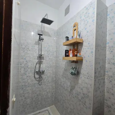 a bathroom with a shower with blue tiles at Appartement Confortable à Chouiter in Chouiter
