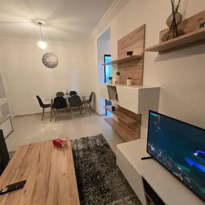 a living room with a television and a table with chairs at Appartement Confortable à Chouiter in Chouiter