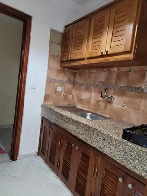 a kitchen with a sink and wooden cabinets at Studio bahaji in Oulad Akkou