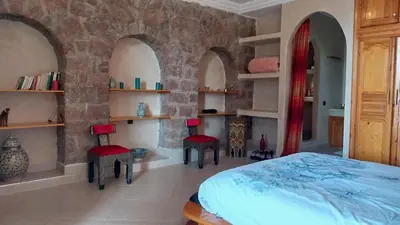 a bedroom with a bed and two chairs and shelves at Beautiful peaceful haven with free breakfast in Aghmat