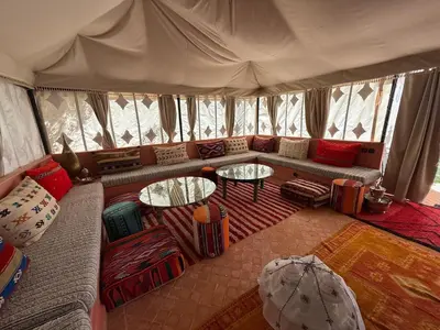 a living room with a couch and tables in a tent at Beautiful peaceful haven with free breakfast in Aghmat