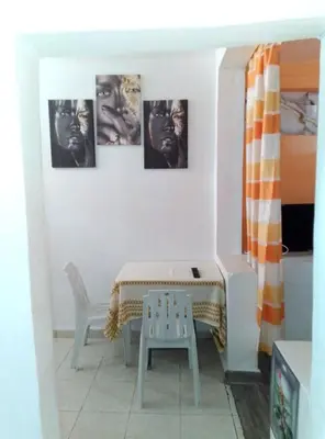 a table and a chair in a room with pictures on the wall at Studio meublé calme in Oulad Akkou