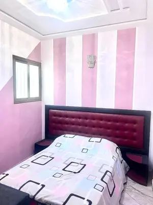 a bedroom with a bed with a red head board at Apparemment 3 chambre in Oulad Akkou