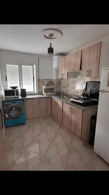 a kitchen with wooden cabinets and a stove top oven at البستان in Oulad Akkou