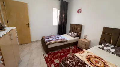 a room with two beds and a door to a bedroom at البستان in Oulad Akkou