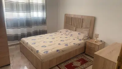 a bedroom with a bed with a wooden headboard at البستان in Oulad Akkou