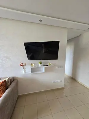 a living room with a couch and a tv on a wall at Appartement de luxe in Ifrane