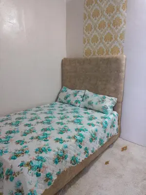a bed with a floral comforter and a pillow at Mom's food in Oulad Akkou