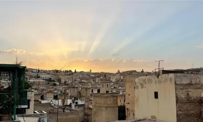 a view of a city skyline with the sun setting at Dar Drouj a Special 14th Century Familyhouse Riad in Fès