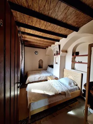 a bedroom with two beds and a wooden ceiling at Riad IZRAREN in FIGUIG in Zenaga