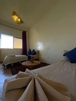 a bedroom with two beds and a living room at Maison D'hôtes Ait Mouli in Bzou