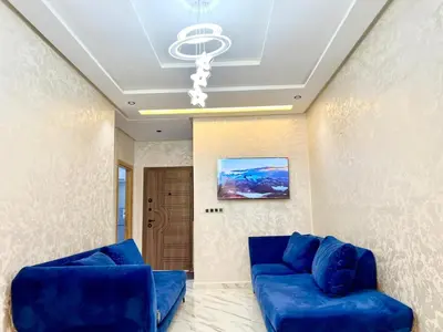 a living room with blue couches and a chandelier at Modern Apartment Fes Near Marjane & Old Medina in Fès