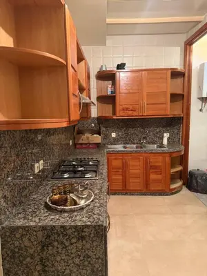 a kitchen with wooden cabinets and a stove top oven at Champ de course in Oulad Akkou