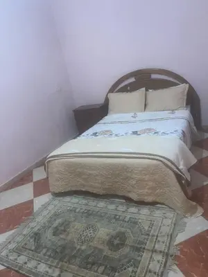a bedroom with a bed with a rug on the floor at Kawtar in Meknès