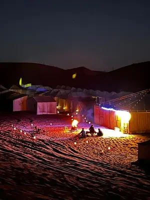 a group of people sitting on a beach at night at Desert Hassi labiad Camp in Merzouga