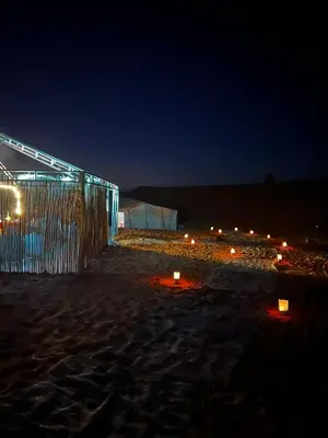 a building on a beach at night with lights at Desert Hassi labiad Camp in Merzouga
