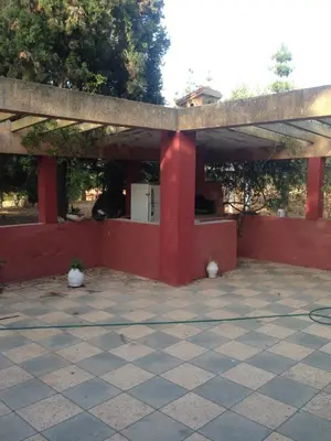 a large pavilion with a red wall at Houria in Oulad Akkou