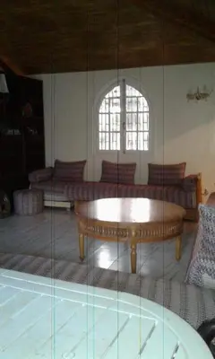 a living room with a table and a glass wall at Houria in Oulad Akkou