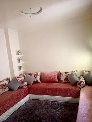 a living room with a red couch with pillows at Malak in Taza
