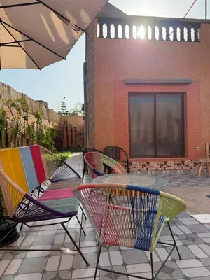 a patio with chairs and a table and an umbrella at Marrakech Private Villa with Pool, Near Ourika and Atlas Mountain in Aghmat