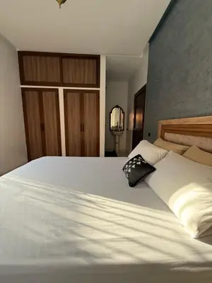 a large white bed with a black pillow on it at Marrakech Private Villa with Pool, Near Ourika and Atlas Mountain in Aghmat