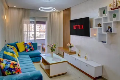 a living room with a blue couch and a tv at Elegance in Oulad Akkou