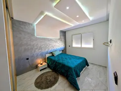 a bedroom with a bed with a green comforter and a window at Yacout 1 in Fès