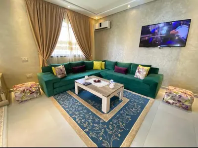a living room with a green couch and a table at Villa Tounaroz in Marrakech