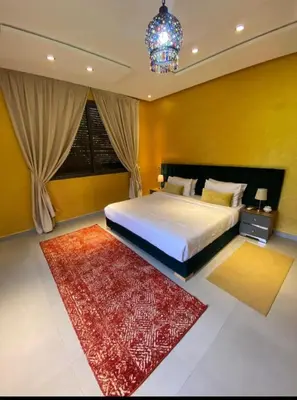 a bedroom with a large bed and a red rug at Villa Tounaroz in Marrakech