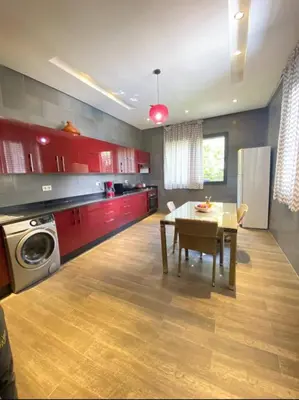 a kitchen with red cabinets and a table and a refrigerator at Villa Tounaroz in Marrakech