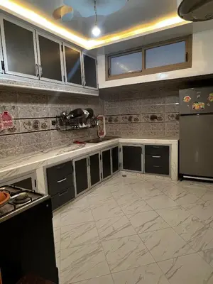 a kitchen with gray cabinets and a black refrigerator at Dakhla in Oulad Akkou