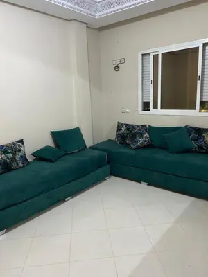 a living room with green couches and a window at Riad ezzaytoune 2 in Meknès