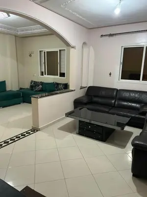a living room with a black leather couch and a table at Riad ezzaytoune 2 in Meknès