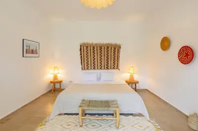 a bedroom with a large bed and two lamps at Le mas de l'Ourika, maison d'hôtes in Aït Zat