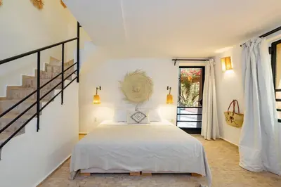 a bedroom with a white bed and a staircase at Le mas de l'Ourika, maison d'hôtes in Aït Zat